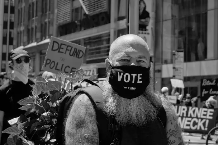 A photo of a person wearing a mask that says "vote"